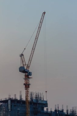 Bomu kule vinç yüksek doğmak bina arasında çelik çerçeve üzerinde kat mülkiyeti inşaat sahasında. Bina inşaat kule vinç ile dramatik gökyüzü arka plan altında üstte gökdelen.