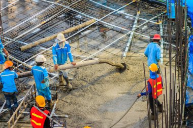 İnşaat işçileri beton sonrası gerginlik döşeme çalışmalarında yağıyor. Mason işçiler iş inşaat sahasında betonlama sırasında hortum beton pompası ya da diğer adıyla fil hortumu taşıyan