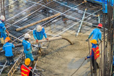İnşaat işçileri beton sonrası gerginlik döşeme çalışmalarında yağıyor. Mason işçiler iş inşaat sahasında betonlama sırasında hortum beton pompası ya da diğer adıyla fil hortumu taşıyan