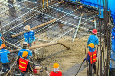 İnşaat işçileri beton sonrası gerginlik döşeme çalışmalarında yağıyor. Mason işçiler iş inşaat sahasında betonlama sırasında hortum beton pompası ya da diğer adıyla fil hortumu taşıyan
