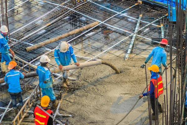 İnşaat işçileri beton sonrası gerginlik döşeme çalışmalarında yağıyor. Mason işçiler iş inşaat sahasında betonlama sırasında hortum beton pompası ya da diğer adıyla fil hortumu taşıyan