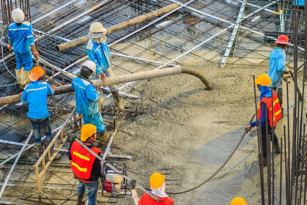 Construction workers are pouring concrete in post-tension flooring work. Mason workers carrying hose from concrete pump or also known as elephant hose during concreting work at construction site