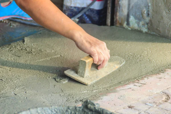 Mason worker use trowel to smooth or leveling liquid concrete of flooring work in step of the building improvement.
