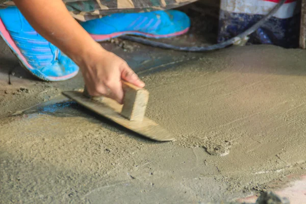 Mason worker use trowel to smooth or leveling liquid concrete of flooring work in step of the building improvement.