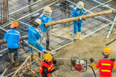 İnşaat işçileri beton takviye formu iş betonlama sırasında sıvı kompakt inşaat alanındaki beton vibratör (benzinli motor tipi) kullanarak kat dökerek eserler.