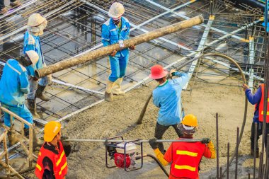 İnşaat işçileri beton takviye formu iş betonlama sırasında sıvı kompakt inşaat alanındaki beton vibratör (benzinli motor tipi) kullanarak kat dökerek eserler.