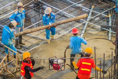 İnşaat işçileri beton takviye formu iş betonlama sırasında sıvı kompakt inşaat alanındaki beton vibratör (benzinli motor tipi) kullanarak kat dökerek eserler.