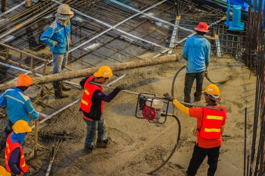 İnşaat işçileri beton takviye formu iş betonlama sırasında sıvı kompakt inşaat alanındaki beton vibratör (benzinli motor tipi) kullanarak kat dökerek eserler.