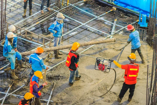 İnşaat işçileri beton takviye formu iş betonlama sırasında sıvı kompakt inşaat alanındaki beton vibratör (benzinli motor tipi) kullanarak kat dökerek eserler.