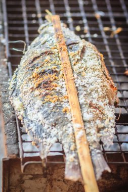 Tuz soba kömür ızgara tilapia balık kaplı. İçinde belgili tanımlık çarşı Caddesi üzerinde Satılık Bambu stick tuz ile kavrulmuş tilapia balık.