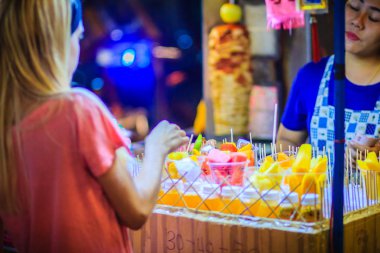 Bangkok, Tayland - 2 Mart 2017: Tanımlanamayan turist Khao San Road gece pazarı, Bangkok, Tayland, sokak gıda satıcısından plastik kap içinde düzenlenmiş dilimlenmiş meyve satın alıyor.