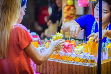 Bangkok, Tayland - 2 Mart 2017: Tanımlanamayan turist Khao San Road gece pazarı, Bangkok, Tayland, sokak gıda satıcısından plastik kap içinde düzenlenmiş dilimlenmiş meyve satın alıyor.