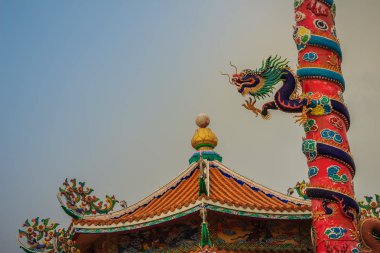 Renkli bir Çinli ejderha heykeli kırmızı ayağı sarılı. Güzel Çin genel tapınak tapınak kutup çevresinde oyulmuş ejderha heykeli.