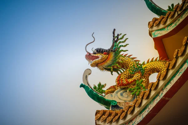 美しい大きな顔をしかめる龍中国の寺院で装飾的なタイル屋根の上をクロールします 青い空を背景に竜の像と伝統的な中国の寺院のカラフルな屋根の詳細 — ストック写真