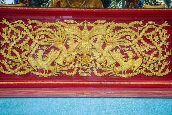 中国の寺院の赤い壁に刻まれている美しい黄金の鳳凰の鳥 — ストック写真
