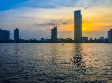 Yüksek katlı condominium ve binaların yapım aşamasında sarı ve mavi gökyüzü arka plan günbatımı sırasında Chao Phraya Nehri manzaralı. Siluet riverfront görünümü gayrimenkul geliştirme.