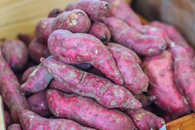 Yerel taze piyasada fiyat etiketi ile satışa organik Japon tatlı patates. Kavrulmuş patates Doğu Asya'da popüler kış sokak yemeğidir. Satılık mor ve sarı tatlı patates.