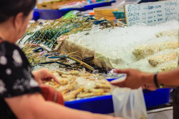 Unidentified woman at the seafood market is buying the extra large size of giant malaysian prawn (Macrobrachium rosenbergii) also known as the giant river prawn or giant freshwater prawn.