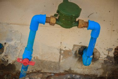 Vintage su sayacı bronz ortak, Pvc Dirsek Bağlayıcısı, mavi Pvc Boru ve grungy duvardaki kırmızı su vanası ile yüklü.