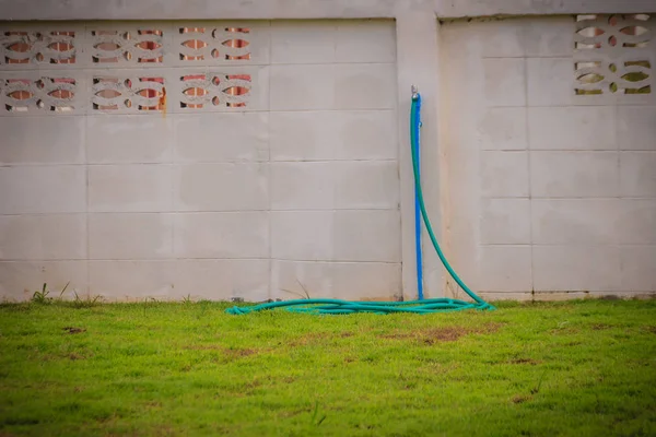 Grungy bronze field faucet connected with blue PVC pipe in white wall background.