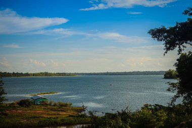 Yeşil çim ve mavi gökyüzü arka plan ile huzurlu mavi göl. Güzel mavi gökyüzü ve bulutlar rezervuar üzerinde. Mavi gökyüzü ve bulutlu gün altında durgun su göle rafting etkinliği.
