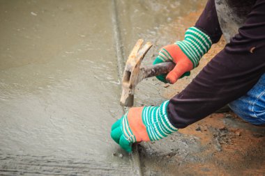 Sıvı beton katılaşmış önce kullanılan işçi tarafından beton kaldırım üzerinde kanal açma beton yüzeyinde pul için çelik bar deforme olmuş. Mason yapışma gücünü artırmak üzere beton döşeme derz dolgu