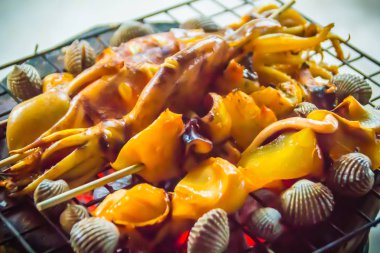 Mürekkep, midye ve istiridye üzerinde gece partide soba kömür ızgara. Deniz ürünleri Barbekü partisi ile kalamar calamaris, midye ve istiridyeler ateşe ızgara. Barbekü kavramı, seçici odak.