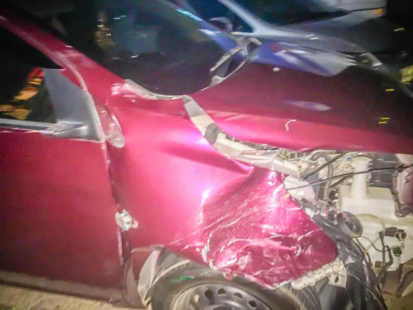 夜に事故で歪んだ赤い新しい車の前面 クラッシュした新しい赤い車は深刻な破損し 修復し 車の保険金請求のため損失アジャスターに呼び出す駐車場への移動のための助けが必要 — ストック写真