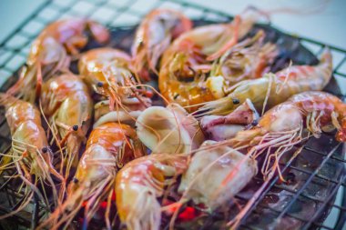 Gece partide ızgara karides ve mürekkep üzerinde kömür sobası. Deniz ürünleri karides ve ateşe Izgara kalamar kalamar ile barbekü partisi. Deniz ürünleri Barbekü kavramı, seçici odak.