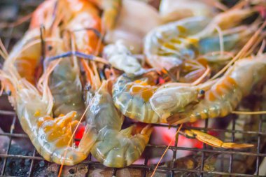 Gece partide ızgara karides ve mürekkep üzerinde kömür sobası. Deniz ürünleri karides ve ateşe Izgara kalamar kalamar ile barbekü partisi. Deniz ürünleri Barbekü kavramı, seçici odak.