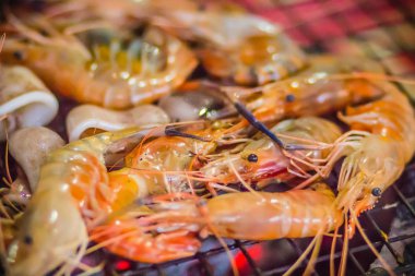 Gece partide ızgara karides ve mürekkep üzerinde kömür sobası. Deniz ürünleri karides ve ateşe Izgara kalamar kalamar ile barbekü partisi. Deniz ürünleri Barbekü kavramı, seçici odak.