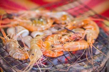 Gece partide ızgara karides ve mürekkep üzerinde kömür sobası. Deniz ürünleri karides ve ateşe Izgara kalamar kalamar ile barbekü partisi. Deniz ürünleri Barbekü kavramı, seçici odak.