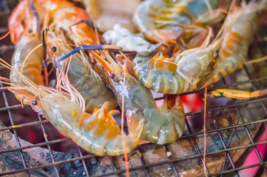 Gece partide ızgara karides ve mürekkep üzerinde kömür sobası. Deniz ürünleri karides ve ateşe Izgara kalamar kalamar ile barbekü partisi. Deniz ürünleri Barbekü kavramı, seçici odak.