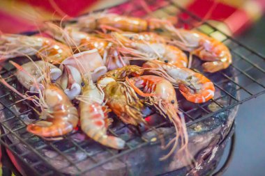 Gece partide ızgara karides ve mürekkep üzerinde kömür sobası. Deniz ürünleri karides ve ateşe Izgara kalamar kalamar ile barbekü partisi. Deniz ürünleri Barbekü kavramı, seçici odak.