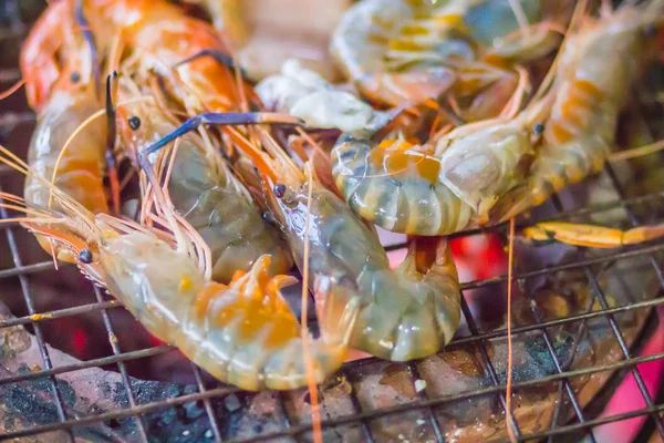 Gece partide ızgara karides ve mürekkep üzerinde kömür sobası. Deniz ürünleri karides ve ateşe Izgara kalamar kalamar ile barbekü partisi. Deniz ürünleri Barbekü kavramı, seçici odak.