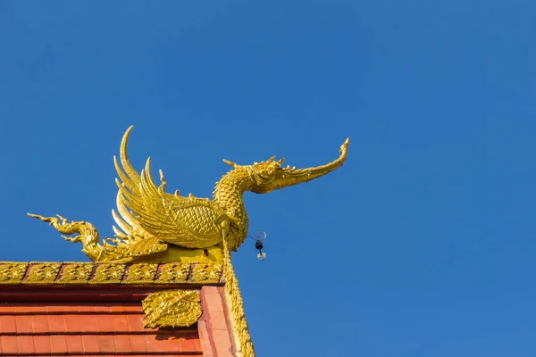タイ北部チェンライ県でワット栄 Suea 青寺としても知られている青い空の背景の下で教会の屋根に美しい白鳥とナガ族の彫刻を見つける — ストック写真