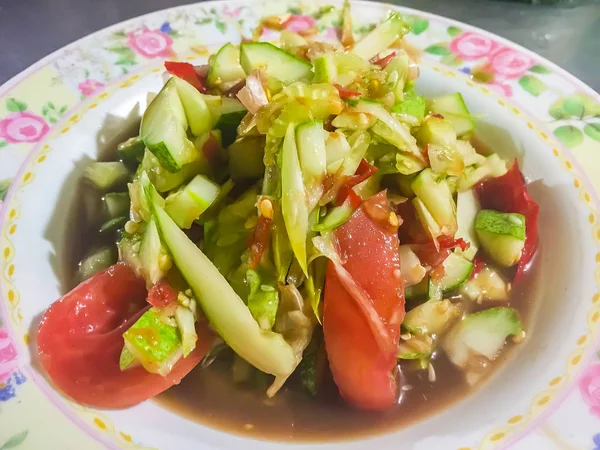 Spicy cucumber salad, Thai street food with tomato and chilli on dish. This spicy Thai cucumber salad has a classic Asian flavor, with a touch of sweetness and a hint of spiciness.