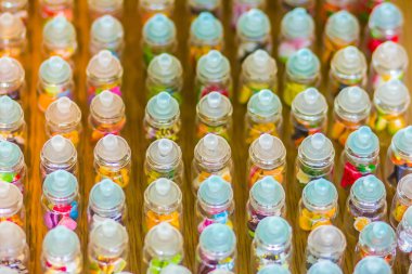 Küçük cam kavanoz Bangkok sokak pazarında satışa renkli kapakları ile satırları