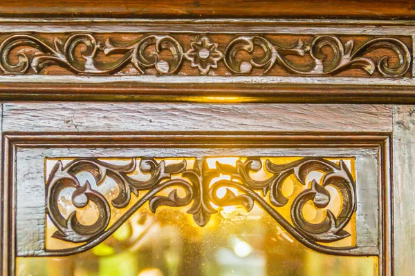 Beautiful patterned on wooden door frame in Thai style carved. Carving pattern of vine and flower in the traditional Thai style on the wooden door of the Thai house. Beautiful wooden craft door frame.