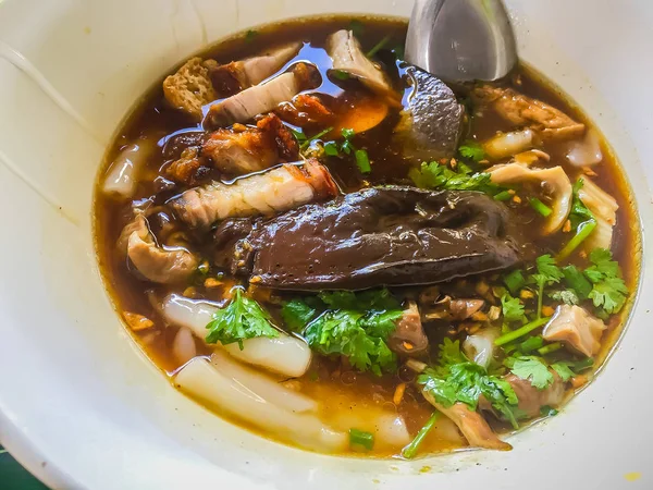 Chinese roll noodle soup or Kuay jub, one of Thai street food that contained noodles roll, pork livers, pork blood, pork kidney, boiled eggs and meat. Large bowl of delicious Chinese roll noodle soup.