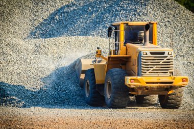Sarı Tekerlekli yükleyici Paletler-Düzleme paleti ezilmiş taş depolama arka planı ocağında çalışıyor.