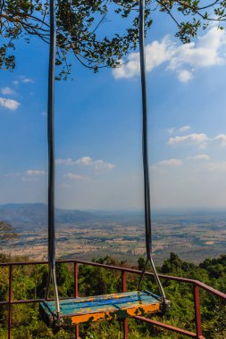 Ağaç dalı ile mavi gökyüzü ve bulutlar beyaz arka plan üzerinde ahşap salıncak asmıştı.