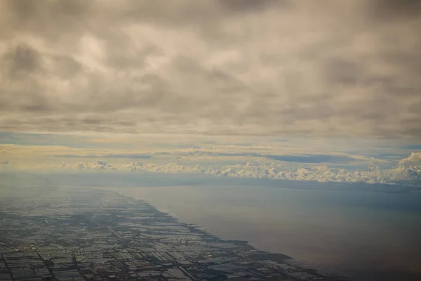 Clouds and sky as seen through window of an aircraft. Exotic view from the window of an airplane flying above the clouds. Beautiful view above the earth at the clouds below.