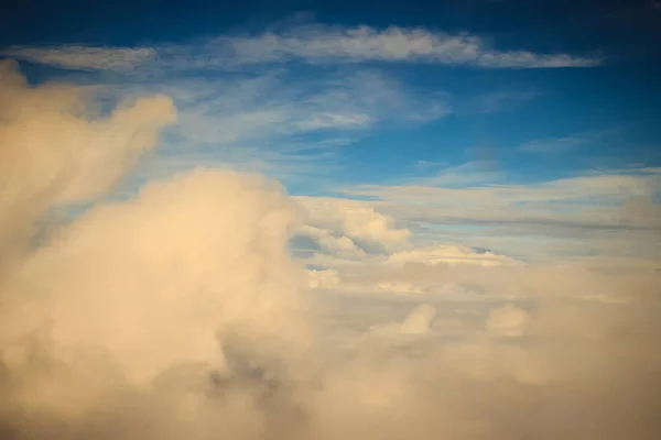 Clouds and sky as seen through window of an aircraft. Exotic view from the window of an airplane flying above the clouds. Beautiful view above the earth at the clouds below.