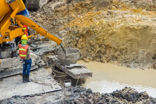 Wet concrete pour or pump from the concrete lorry into the bore pile casing. Bored piles are piles where the removal of spoil forms a hole for a reinforced concrete pile which is poured in situ. — Stock Image Wet Concrete Pour Pump Concrete Lorry Bore Pile Casing Bored Stock Picture