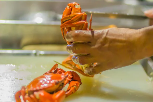 Close up hand of chef in restaurant during cut the steamed crab before serve to the customer.