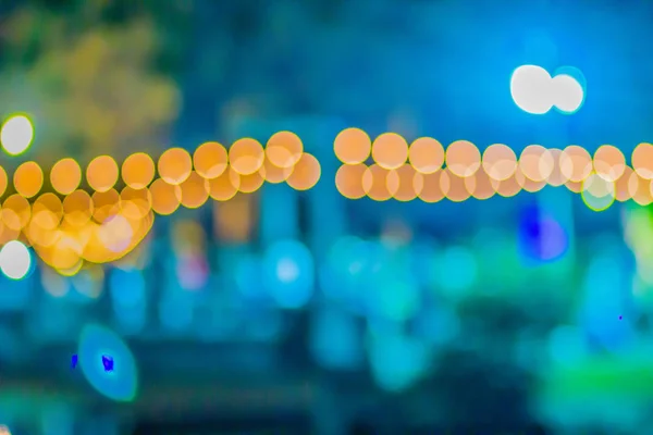 Blurred light with bokeh background of temple fair in Thailand. Walking street market with blurred people and bokeh light. Abstract blurred circular bokeh background.