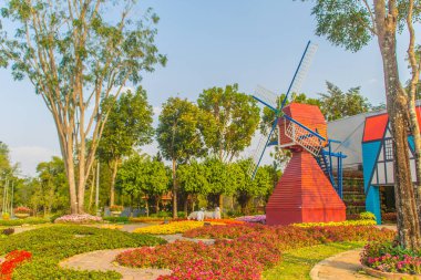 Güzel kırmızı rüzgar değirmeni genel parkta kırmızı çiçek bahçesinde.