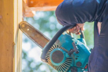 Marangoz benzin motoru taşınabilir elektrikli testere dikey oluk hattına ahşap kesme kullanıyor. Benzin kullanarak marangoz El motor taşınabilir elektrikli testere kesim ahşap bina inşaat alanı.