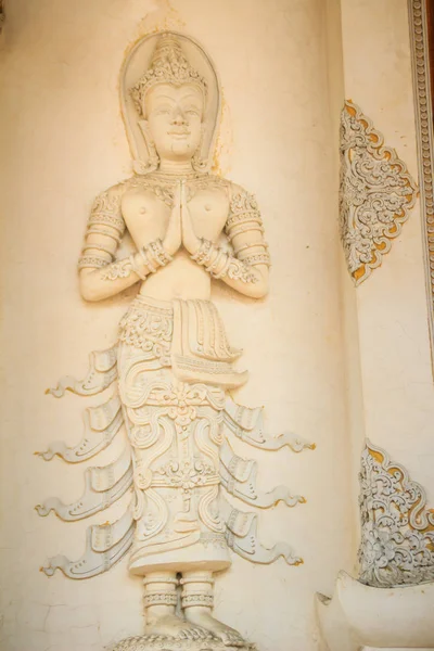 Cement angel craved in act paying respect to welcome to the public Buddhist temple. Thai style crafted stucco angel is acting Wai or Sawasdee. Sawasdee is the word to use for greetings and goodbye.